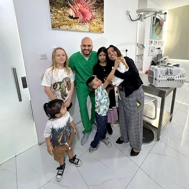 Dr Furkan with a happy family and their ginger and white cat