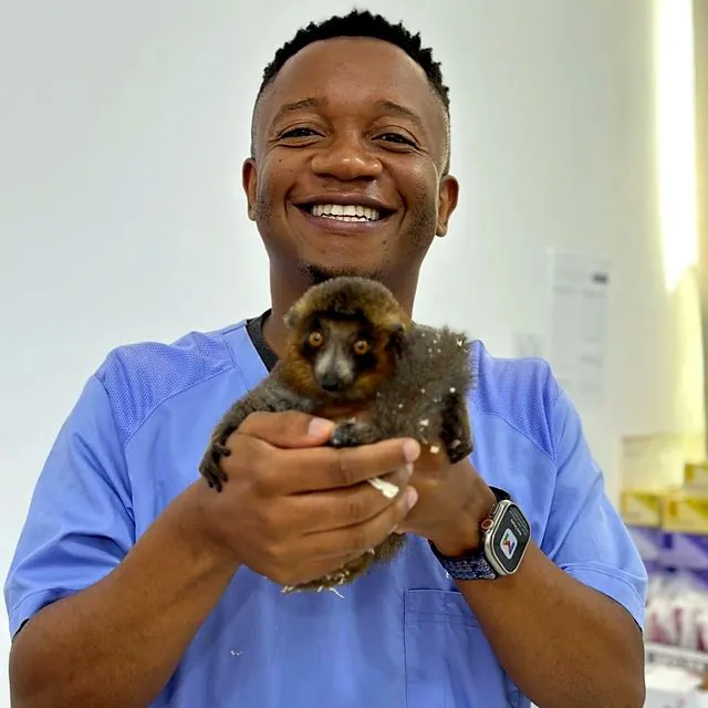 Dr Tinashe smiling with a young lemur in his hands