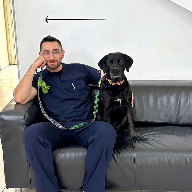 Dr Eren relaxing on the sofa with a black Labrador
