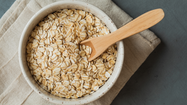 a bowl of uncooked oats with a wooden spoon dipped on it